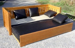 Shown open with top cushion lowered to become a bed.